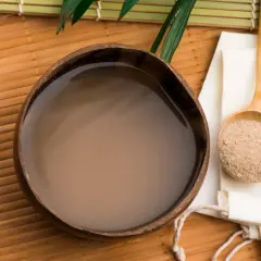 Jak przygotować kava kava: napój w kokosowej misce obok łyżki z proszkiem.