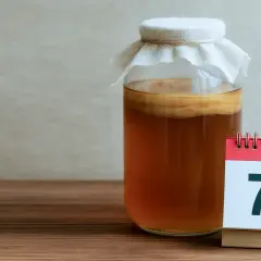 Siedem dni fermentacji herbaty. Słoik z kombuchą i kalendarz z cyfrą 7.