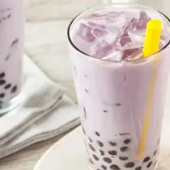 Fioletowe bubble tea z tapioki, orzeźwiające i słodkie, z widocznymi czarnymi kuleczkami na dnie szklanki.