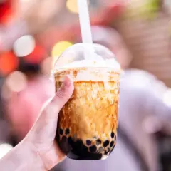 Ręka trzyma kubek z brązowym bubble tea. Czy bubble tea jest zdrowe? Zależy od składników, ale ten wygląda pysznie!