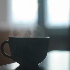 Ciemna filiżanka parującej herbaty na stole. Zastanawiam się, ile miodu do herbaty dodać, by była idealna.