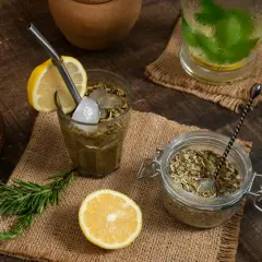 Orzeźwiająca yerba mate cytrynowa z lodem i rozmarynem, obok słoik z suszem i cytryna.