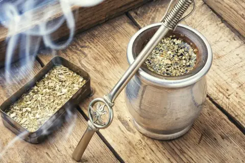 Gorąca yerba mate, parująca z metalowego naczynia, obok pojemnika z suszem. Czas na odkrycie jej wyjątkowego smaku.