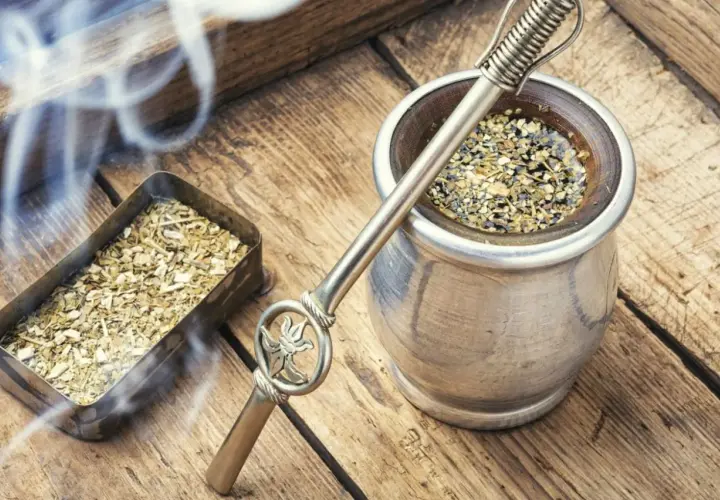 Gorąca yerba mate, parująca z metalowego naczynia, obok pojemnika z suszem. Czas na odkrycie jej wyjątkowego smaku.