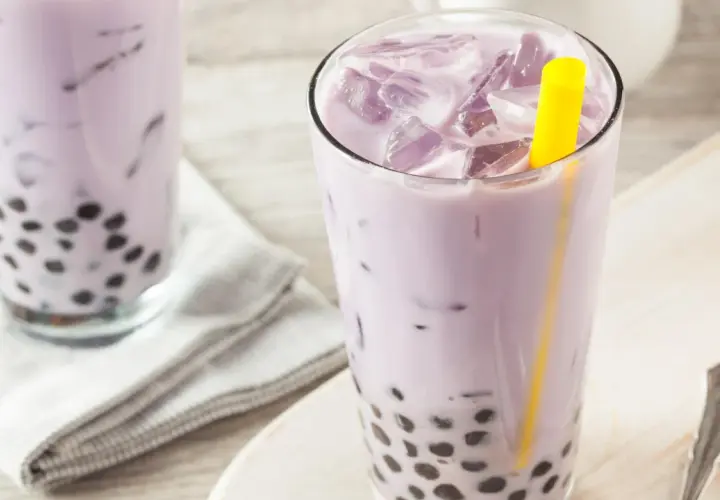 Fioletowe bubble tea z tapioki, orzeźwiające i słodkie, z widocznymi czarnymi kuleczkami na dnie szklanki.