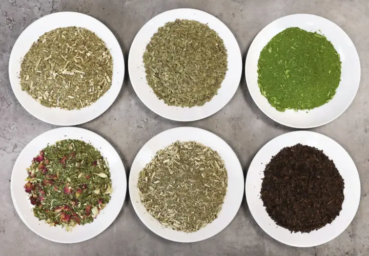 Sześć talerzy z różnymi rodzajami yerba mate, od zielonej po ciemnobrązową. Poznaj fascynujące verde mate właściwości!