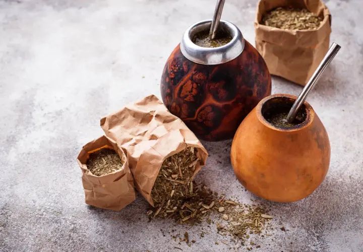 Dwa tykwy z yerba mate i bombillami, obok papierowe torebki z suszem. Czy yerbę można słodzić? To zależy od preferencji!