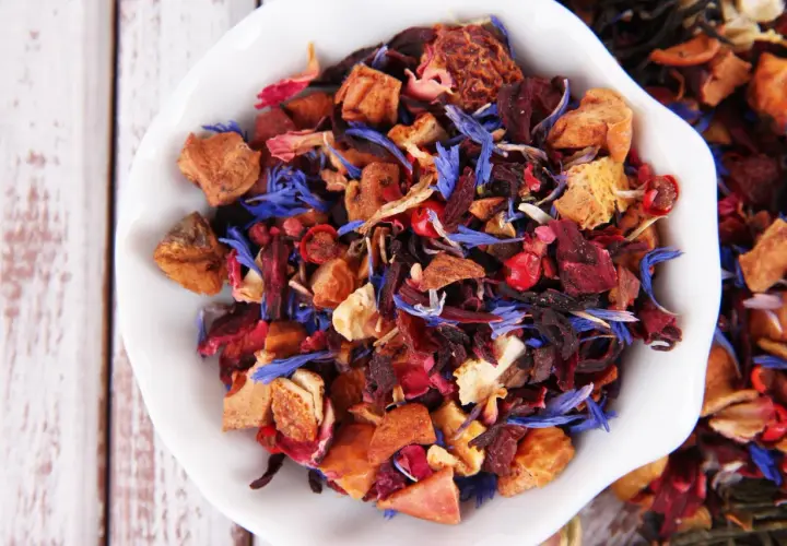 Mieszanka suszone owoce do herbaty: kawałki jabłek, hibiskus, płatki róży i chabru tworzą barwny bukiet.
