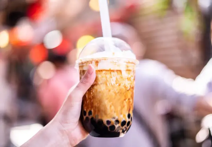 Ręka trzyma kubek z brązowym bubble tea. Czy bubble tea jest zdrowe? Zależy od składników, ale ten wygląda pysznie!