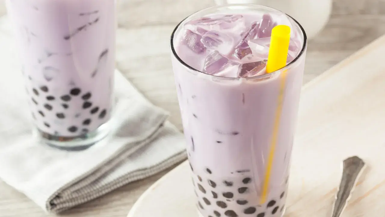 Fioletowe bubble tea z tapioki, orzeźwiające i słodkie, z widocznymi czarnymi kuleczkami na dnie szklanki.