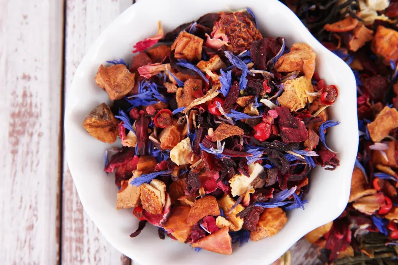 Mieszanka suszone owoce do herbaty: kawałki jabłek, hibiskus, płatki róży i chabru tworzą barwny bukiet.