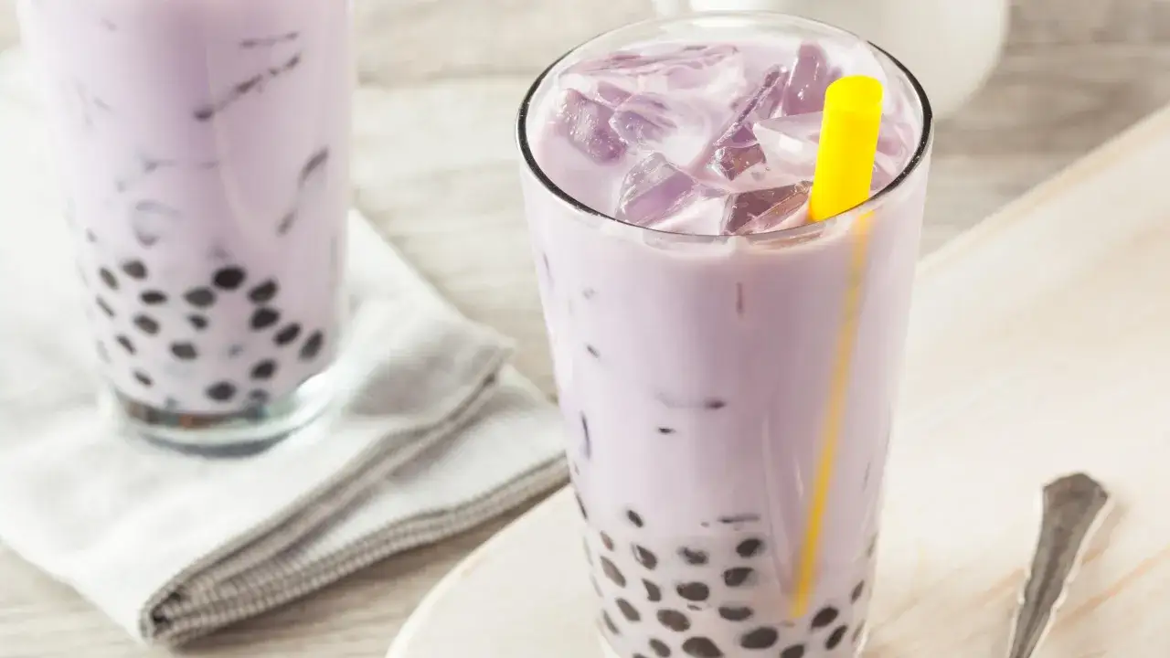 Fioletowe bubble tea z tapioki, orzeźwiający napój z lodem i żółtą słomką.