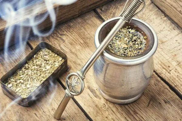 Gorąca yerba mate, parująca z metalowego naczynia, obok pojemnika z suszem. Czas na odkrycie jej wyjątkowego smaku.